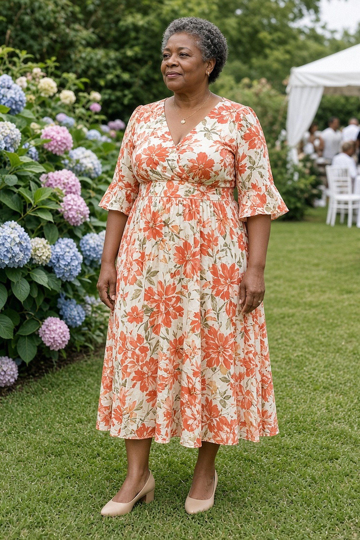 Woman over 50 in a coral floral midi tea dress with elbow sleeves by hydrangeas