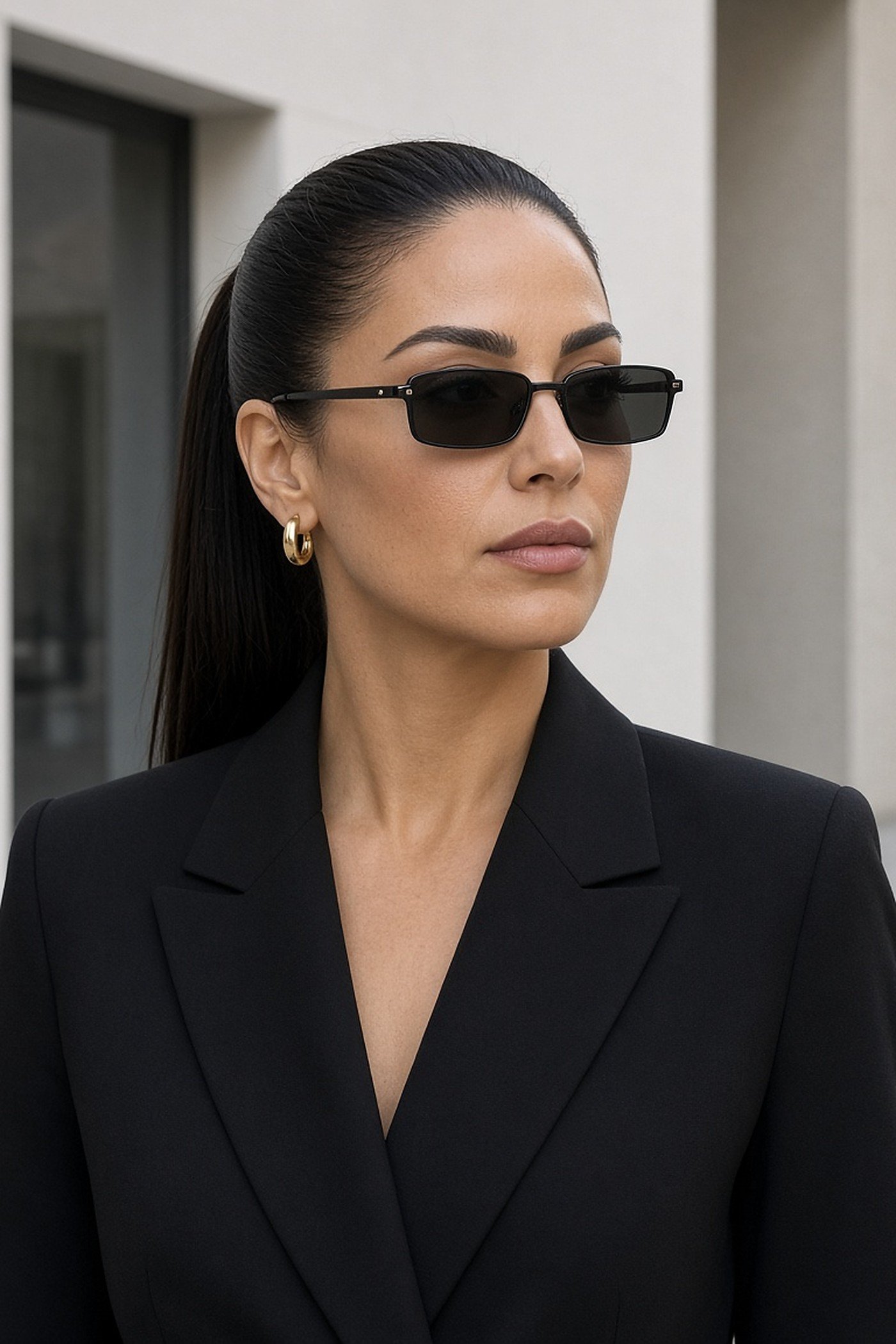 Woman in her 30s in slim rectangle black sunglasses and a black blazer